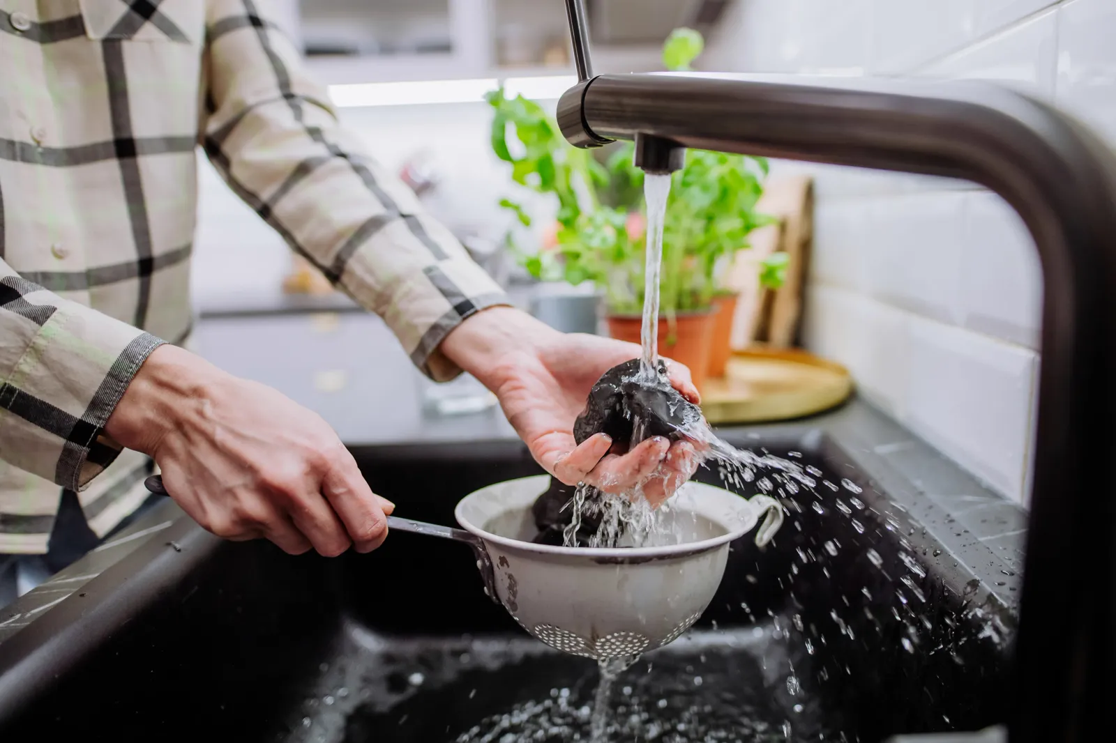 Hands washing fresh fruit at a kitchen sink — clean, well-filtered water is the foundation; alkalinity is a meaningful add-on on top